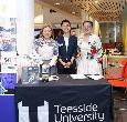Three Alumni at a Teesside University branded desk