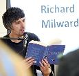 Richard Milward sitting in a room reading from one of his books