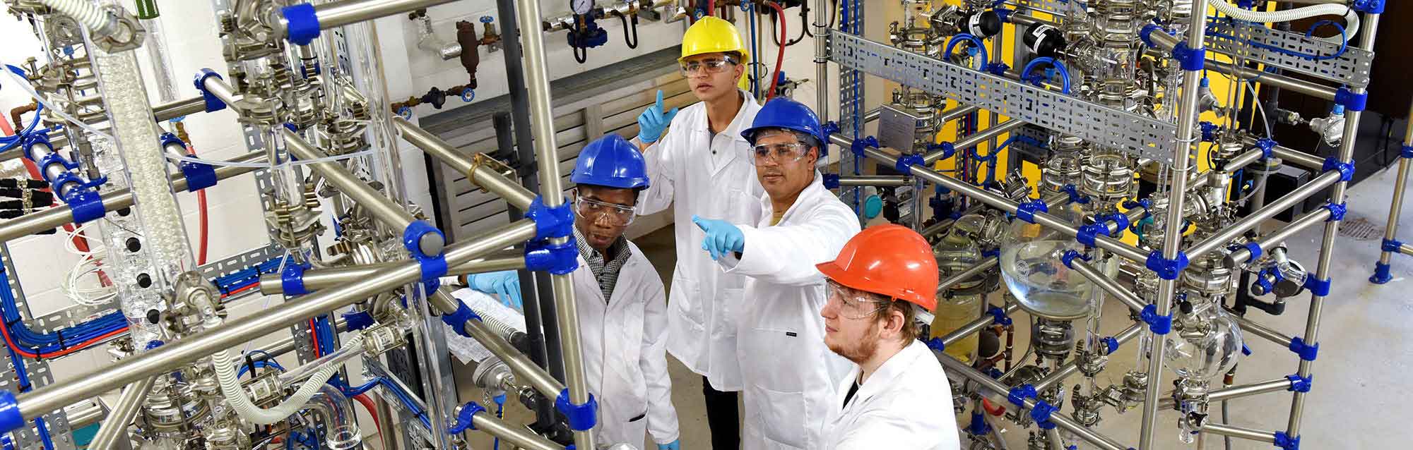 Students looking at a distillation column, Chemical Engineering Degree