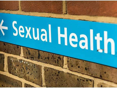 Sign (white text on blue background), on a wall, with the words 'Sexual Health'. Link to Testing Tuesdays: Sexual health drop-ins, 2025-26.