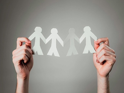 Two hands holding up a row of cut out paperchain people.. Link to Restorative Justice – support and recovery .