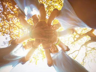 Group of volunteers, with hands together, photographed from below.. Link to Group of volunteers, with hands together, photographed from below..