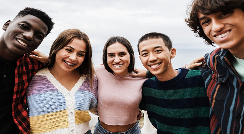 A group of 5 people standing together and smiling