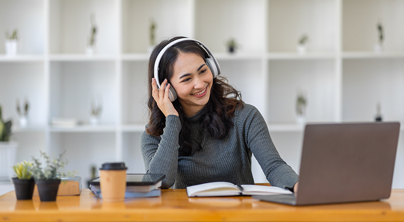 Student in an online session (with a laptop and note book, wearing headphones)