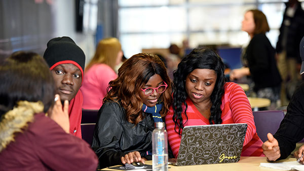 Group of students seated around a table working with a computer at Teesside University