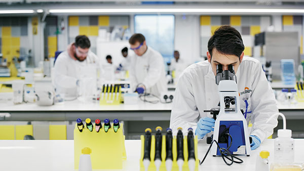Postgraduate research student using a microscope in a laboratory at Teesside University