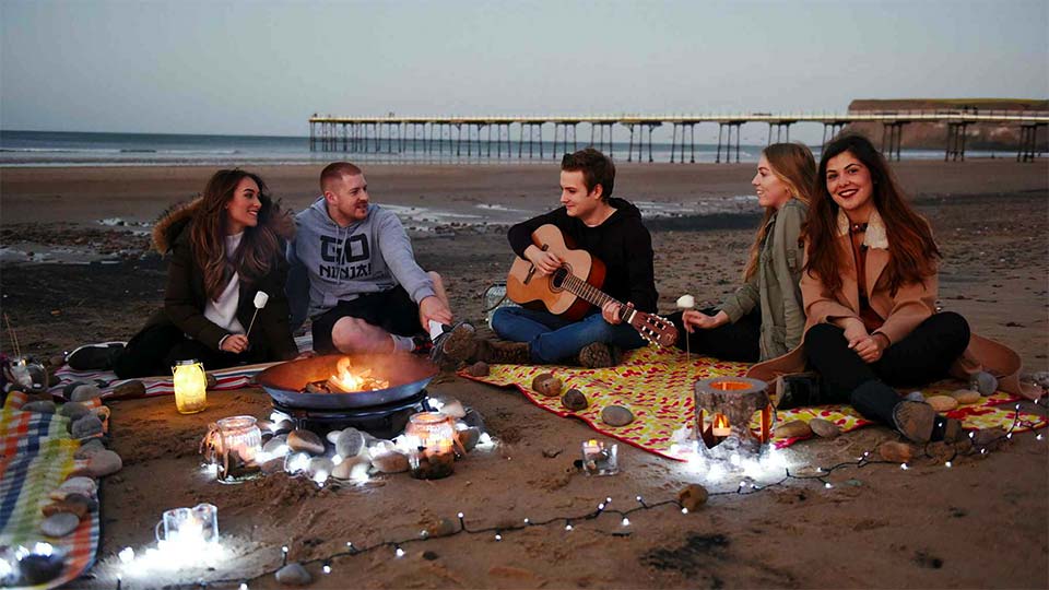 Students sat on the beach at Saltburn