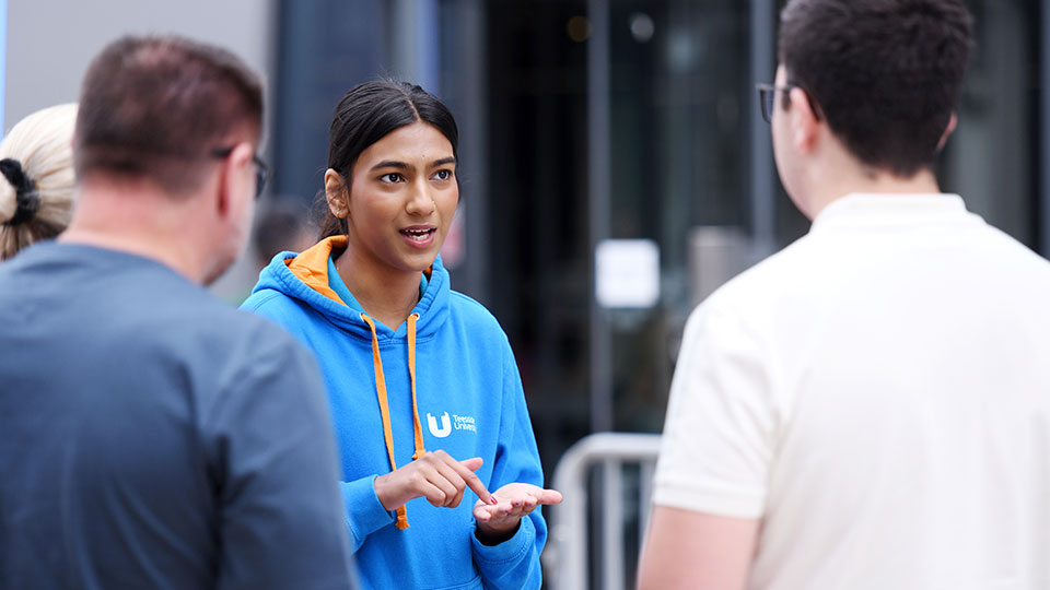 University ambassador speaking with two prospective students at an open day UCAS exhibition stand