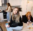 A group of students in a shared kitchen space: a few are seated at a table working on a jigsaw puzzle