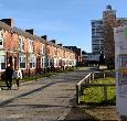 Students crossing the street outside King Edwards Square at Teesside University with surrounding buildings in view