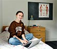 Student on a bed in a private bedroom at King Edwards Square Teesside University with small table visible in the background