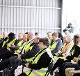 A group of people wearing yellow high-visibility vests seated and listening to a presentation or event at the Teesside Digital Trade Testbed.