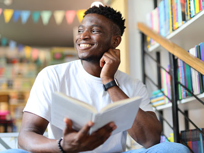 An image of a person smiling whilst holding a book.. Link to National Year of Reading - Mood Boosting Books.