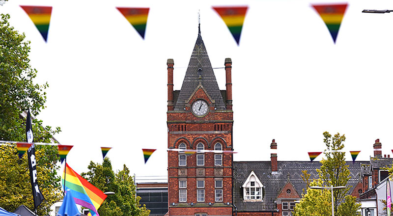 The Waterhouse Building clock tower at Teesside University, with pride flags in the foreground