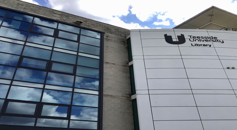 An image of Teesside University library, with clouds reflected in the windows.