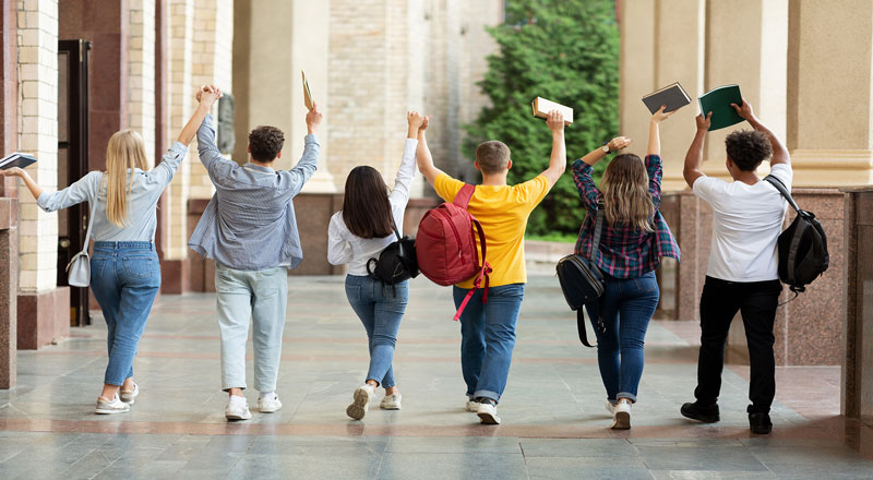 A group of students wakling along with their hands in the air in celebration
