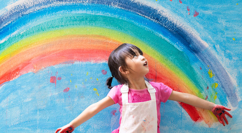 An image of a child looking at a painted rainbow