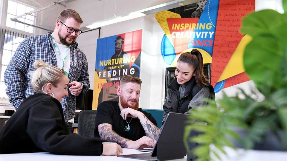A group of students discussing their work round a laptop 