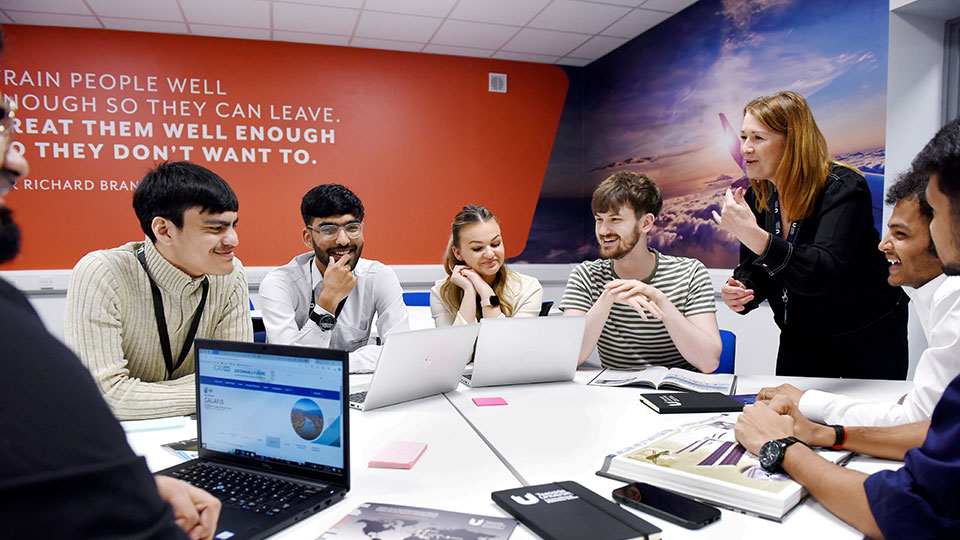 Staff and students collaborating around a table with laptops at Teesside University