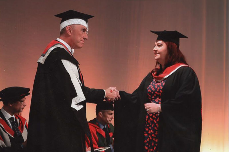 Andrea Burrows in her graduation day shaking hands with VC
