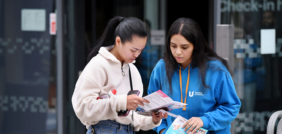 Ambassador and student pointing a leaflet in an open day