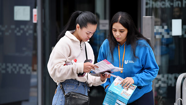 Ambassador and student pointing a leaflet in an open day