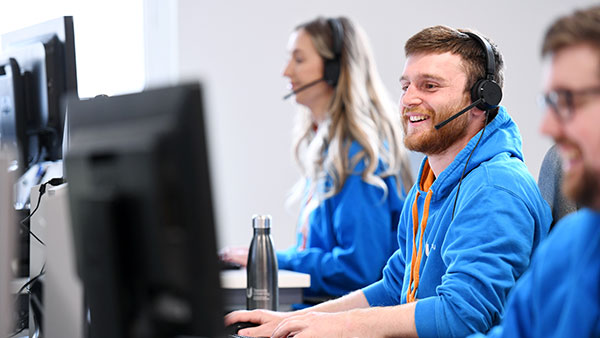 Support staff in front of their computers helping students on a clearing day