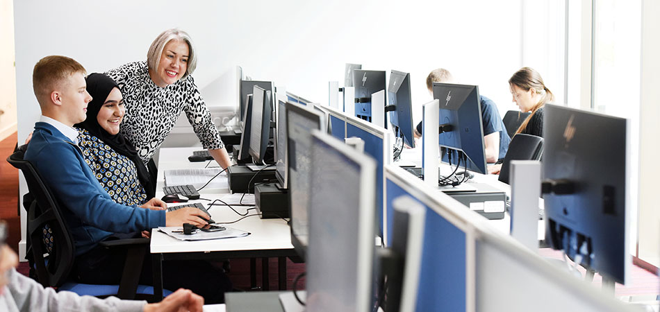 Students and staff in a University lab pointing at the compuer screen