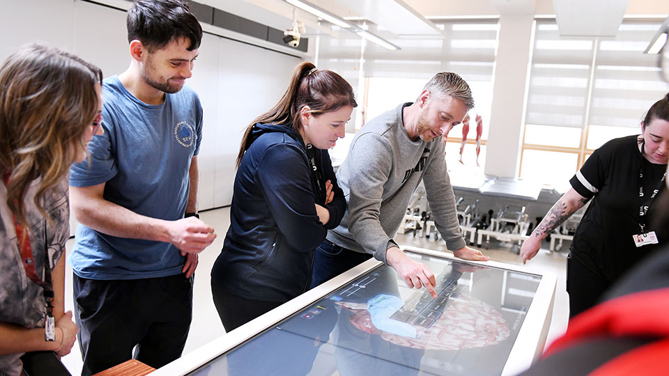 Students and teacher in a class of BIO touching a big screen