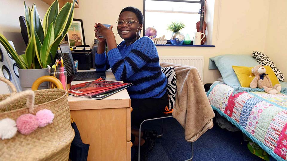 Student sitting at her desk in accommodation room at Teesside University