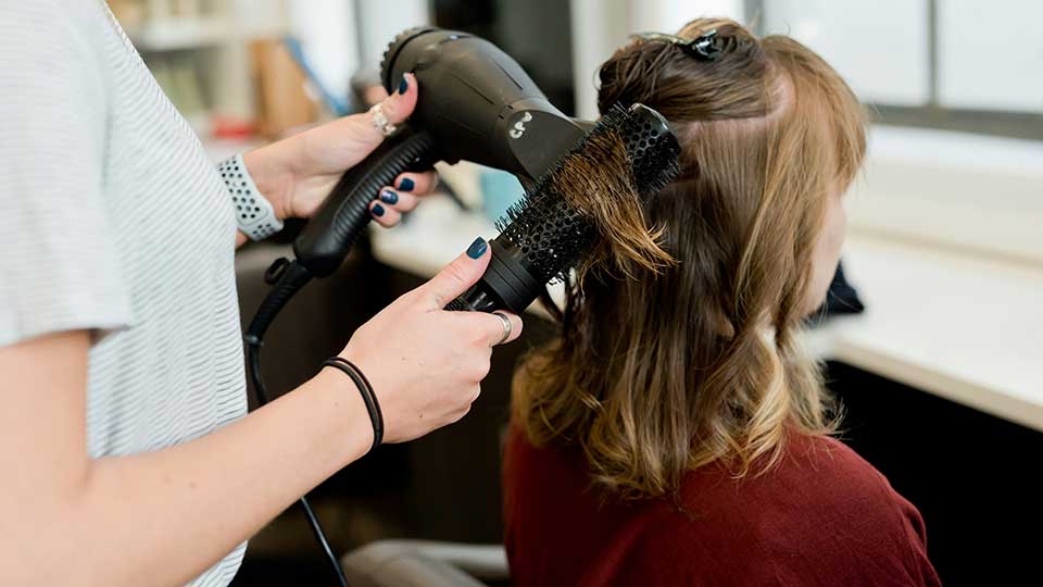 Hairdresser styling a woman's hair with a blow dryer in a salon