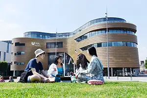 Teesside University campus showing the curve building with international students sit in the grass