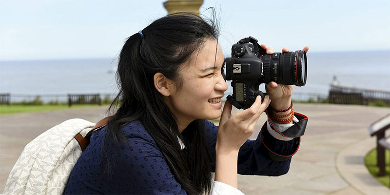 International student with a camera enjoying the seaside in the UK