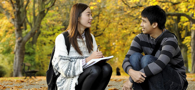 Two international students sitting in a UK park, settling in after arrival