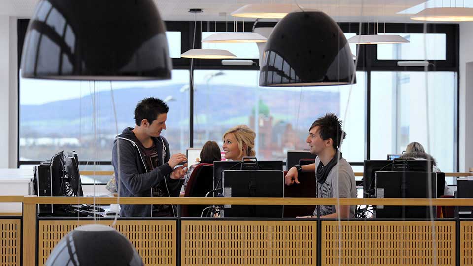 Students and staff collaborating at desks inside a Teesside University building