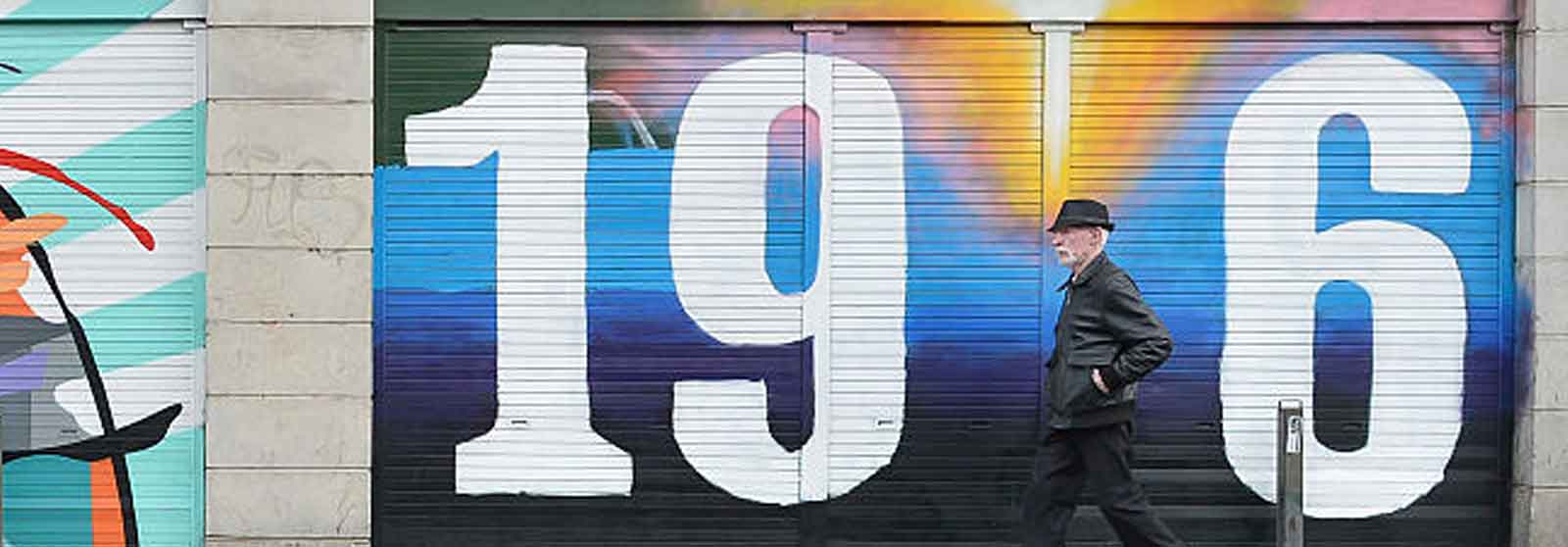 Man walking down a street lined with colorful wall paintings or murals