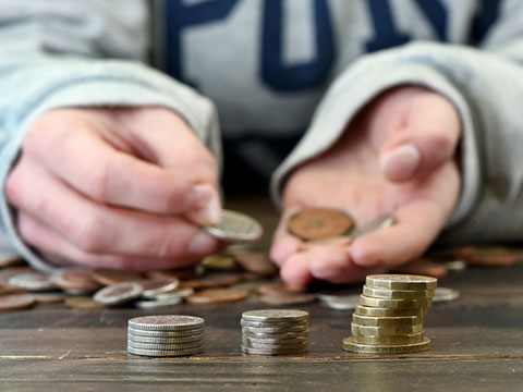 Hands sorting coins on a table reflecting student finance management