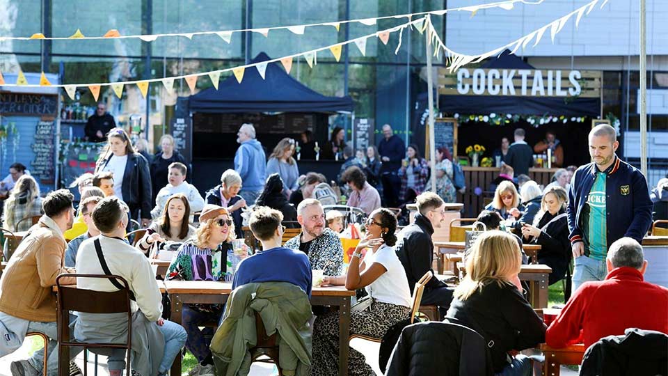 Students sitting on the grass and standing by stalls at Orange Pip Market in Middlesbrough