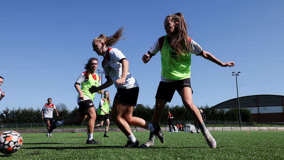 Female students playing football on the campus fields at Teesside University