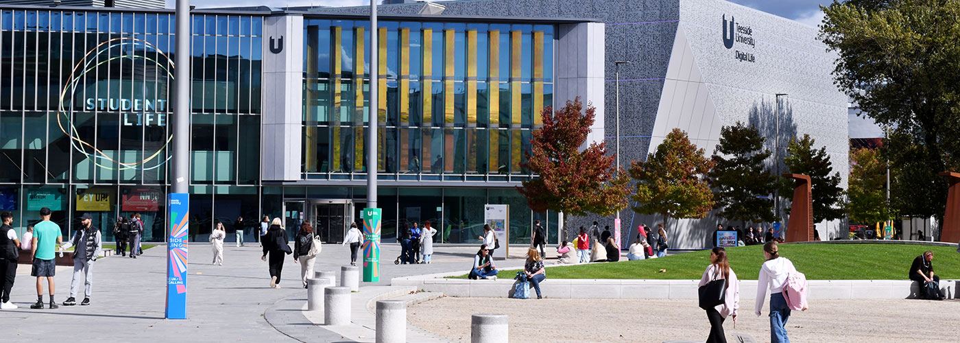 Teesside University campus showing Student Life and Digital Life buildings with students walking and relaxing outdoors