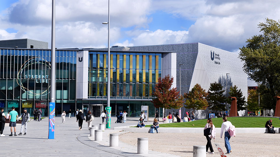 Teesside University campus showing Student Life and Digital Life buildings with students walking and relaxing outdoors
