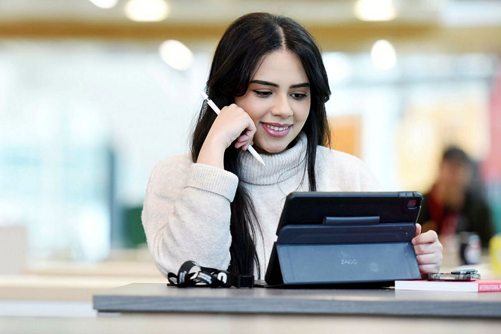 Business student working on a laptop in a campus building